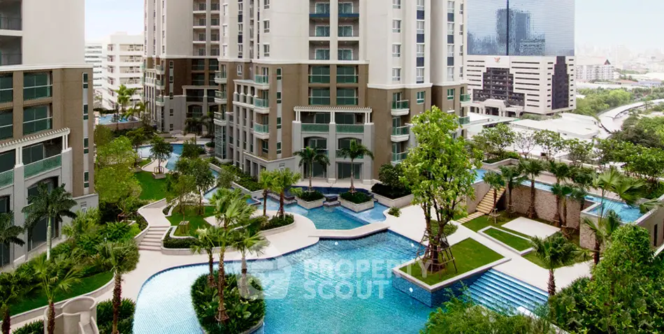 Luxurious residential complex with stunning pool and lush gardens in urban setting.