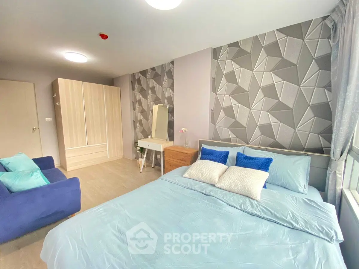 Modern bedroom with stylish geometric wallpaper and cozy blue bedding