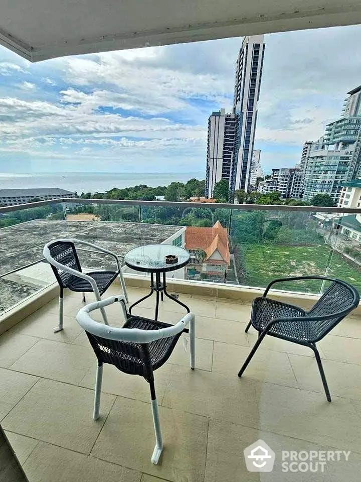 Stunning balcony view with modern seating overlooking city skyline and ocean horizon.