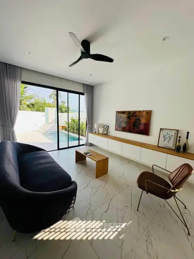 Modern living room with pool view, sleek furniture, and large sliding glass doors.
