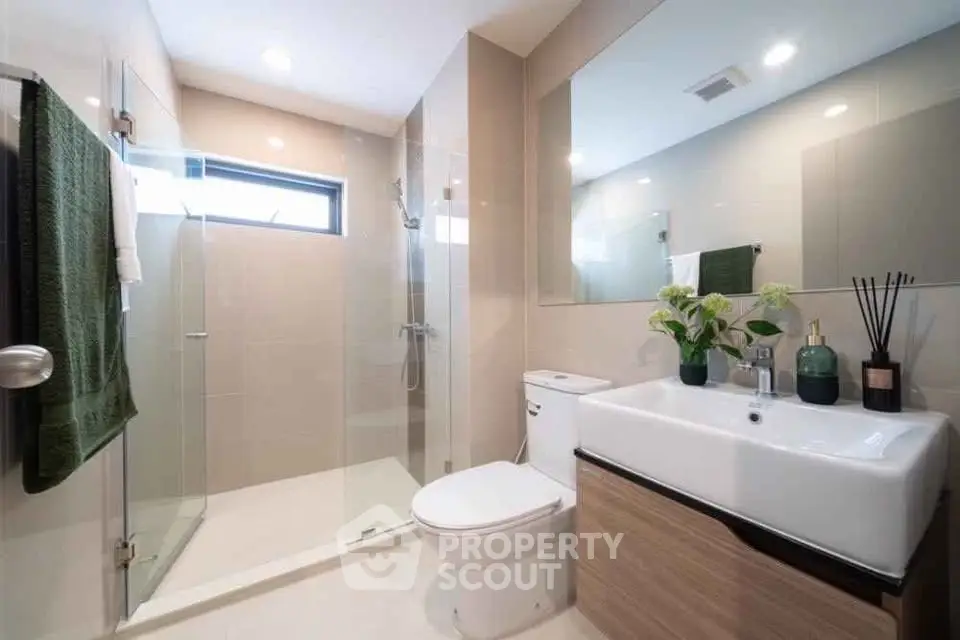 Modern bathroom with sleek design, featuring a glass shower, large mirror, and elegant sink.