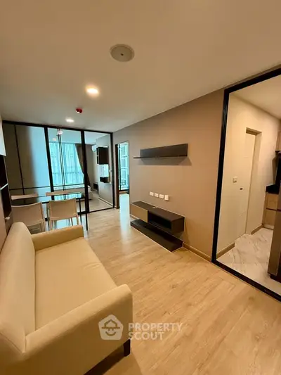 Modern living room with beige sofa, dining area, and open layout in a stylish apartment.