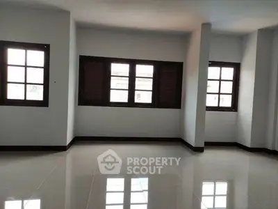 Spacious empty room with large windows and glossy tiled floor