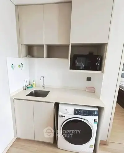Compact modern kitchen with integrated washing machine and microwave, ideal for urban living.