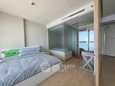 Modern bedroom with glass-enclosed bathroom and ocean view