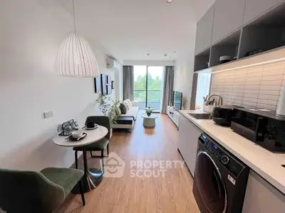 Modern open-plan living room with kitchen, featuring stylish decor and natural light.