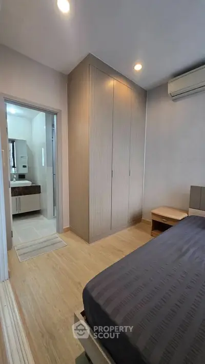 Modern bedroom with ensuite bathroom and built-in wardrobe, featuring sleek design and cozy ambiance.