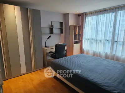 Modern bedroom with stylish furniture and large window offering natural light.