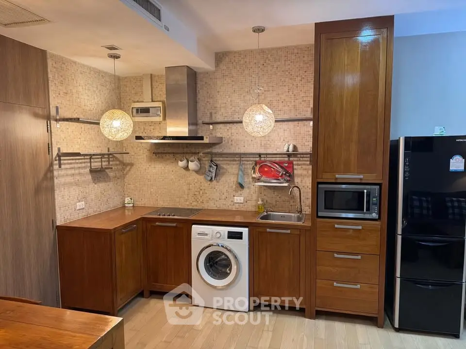 Modern kitchen with wooden cabinets, washing machine, and sleek appliances in a cozy apartment.