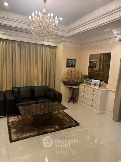 Elegant living room with chandelier, leather sofa, and marble coffee table in luxurious home.