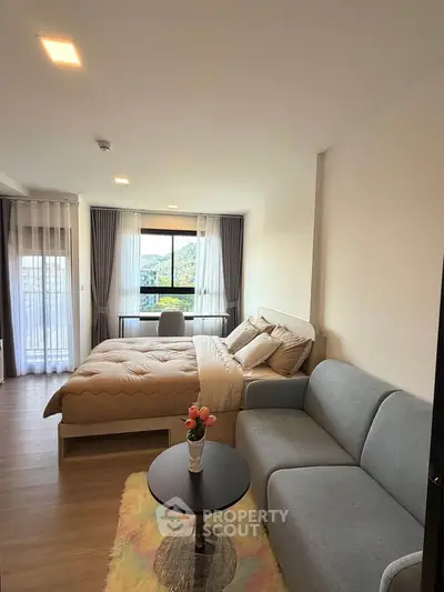 Modern studio apartment with cozy bed, stylish sofa, and scenic window view.