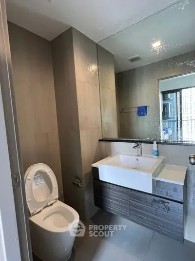 Modern bathroom with sleek design and large mirror in urban apartment.