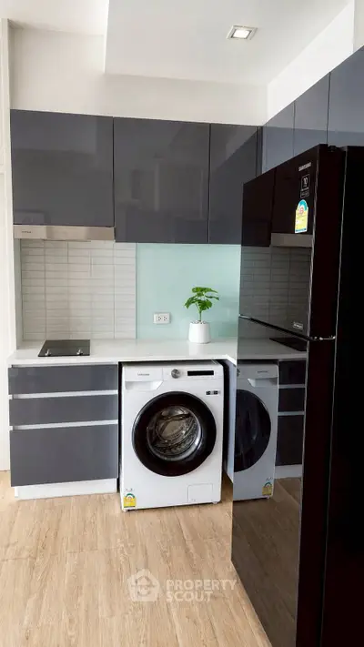 Modern kitchen with sleek cabinets, washing machine, and black refrigerator
