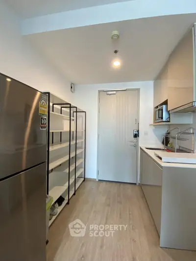 Modern kitchen with sleek cabinets and stainless steel fridge in a compact layout.