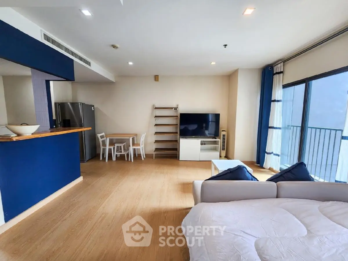 Spacious open-plan living room with modern kitchen and balcony access