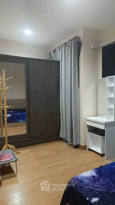 Cozy bedroom with wooden flooring, mirrored wardrobe, and stylish curtains for a modern living experience.
