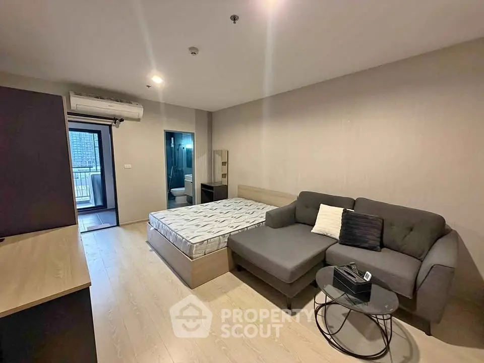 Modern studio apartment with cozy living area and bed, featuring a sleek design and balcony access.