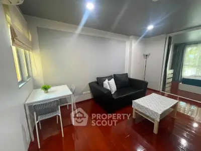 Modern living room with sleek furniture and wooden flooring in a cozy apartment setting.