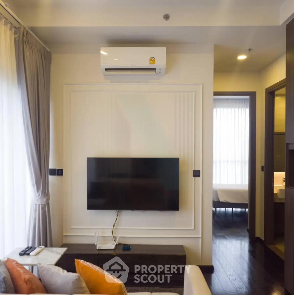 Modern living room with wall-mounted TV and air conditioning, featuring elegant decor and natural light.
