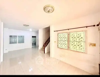 Spacious empty living room with tiled floor and staircase, ready for customization.