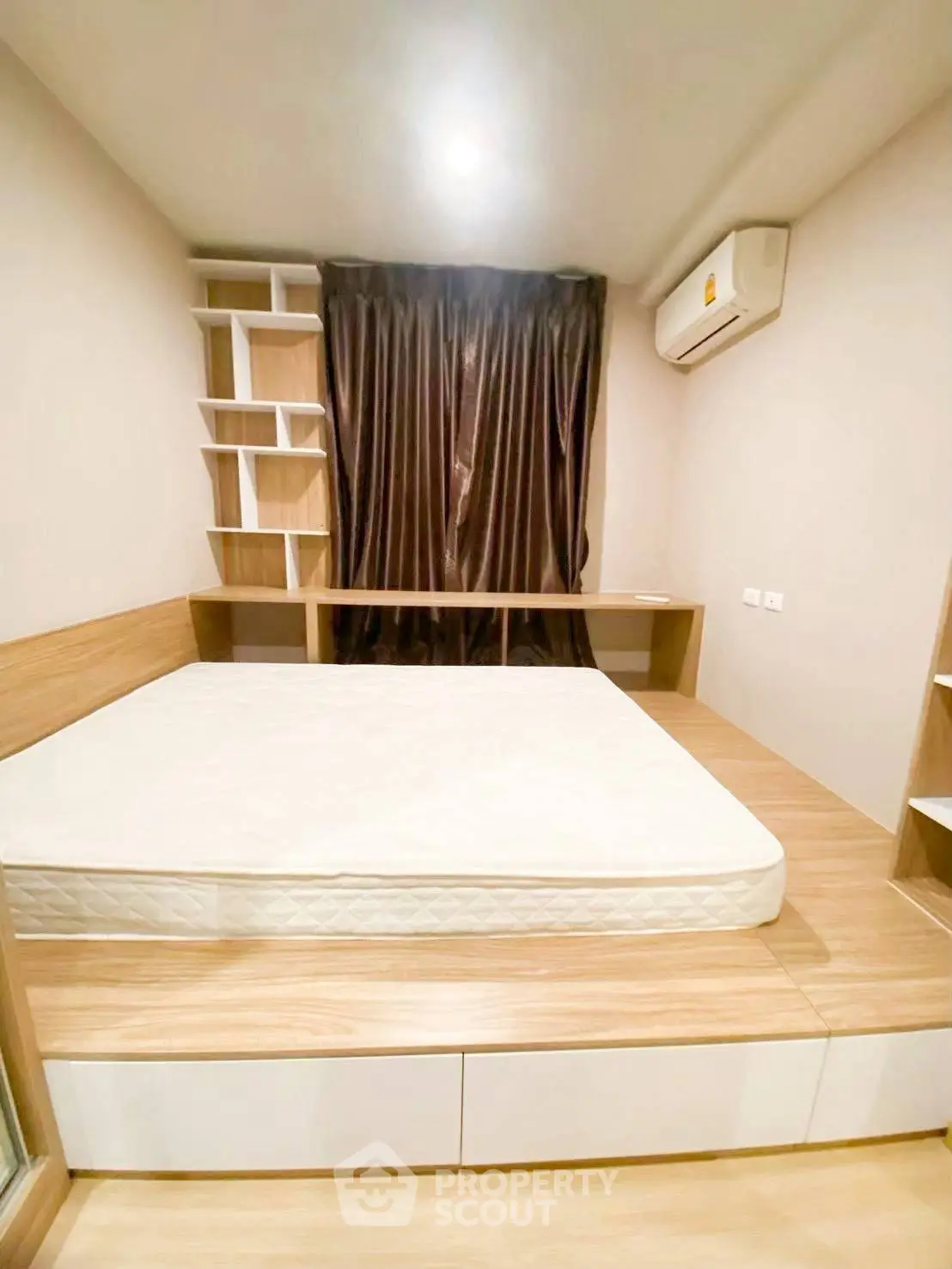 Modern bedroom with built-in wooden furniture and air conditioning, featuring a cozy bed and stylish shelving.