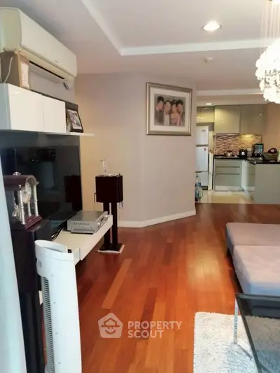 Spacious living room with wooden flooring and modern kitchen in open layout apartment.