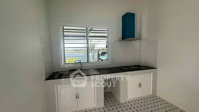 Modern kitchen with sleek countertops and gas stove, featuring a bright window view.