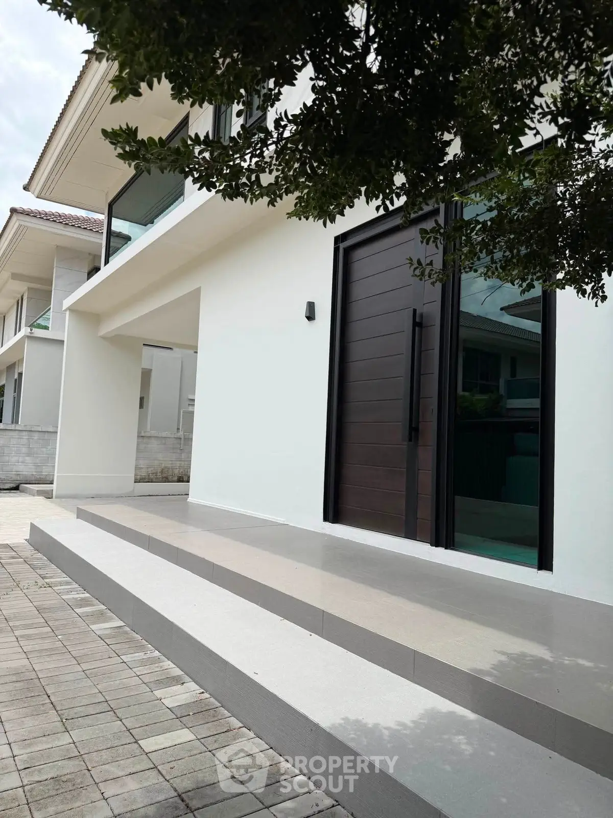 Modern white house exterior with sleek entrance and large windows, showcasing contemporary architectural design.