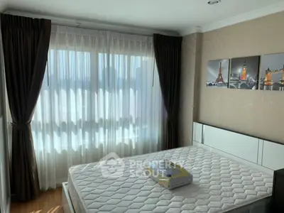 Bright bedroom with large window and elegant curtains, featuring a comfortable bed and stylish wall art.