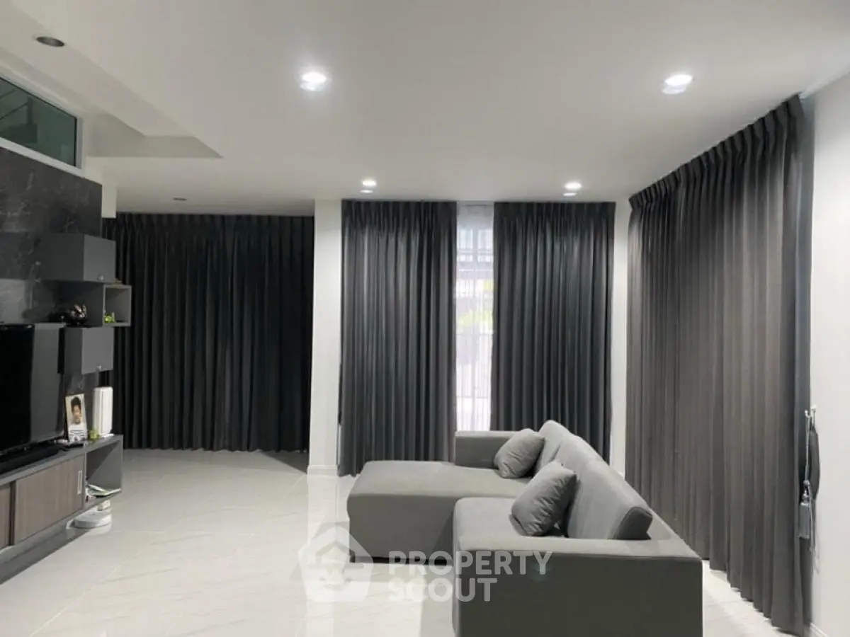 Spacious modern living room with sleek gray sofa and elegant curtains