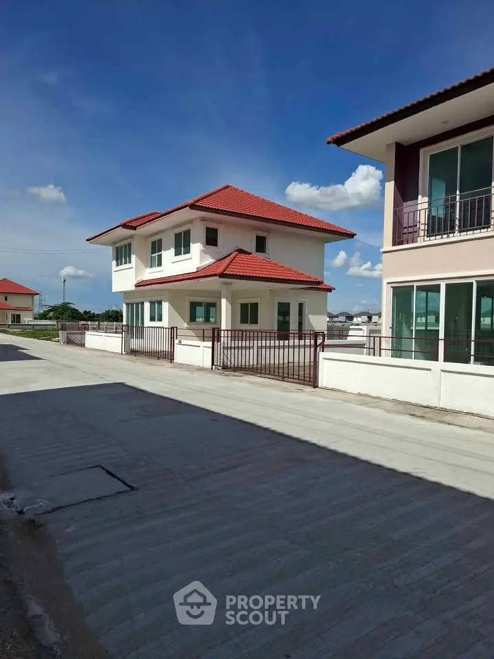 Charming two-story house with red roof and spacious driveway in a serene neighborhood.