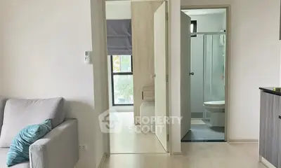 Modern apartment interior with cozy living room and bathroom view, featuring sleek design and natural light.
