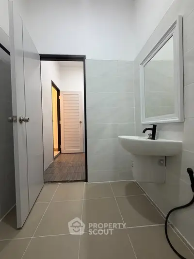 Modern bathroom with sleek design and neutral tiles, featuring a wall-mounted sink and contemporary fixtures.
