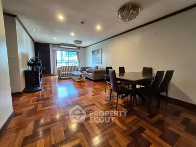 Spacious living room with elegant parquet flooring and modern furniture in a well-lit apartment.