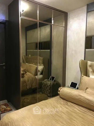 Elegant bedroom with mirrored wardrobe and plush bedding in modern apartment.