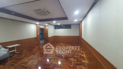 Spacious room with wooden flooring and recessed lighting, ideal for versatile use.