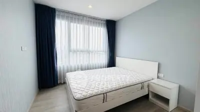 Spacious bedroom with large window and modern decor in a stylish apartment.