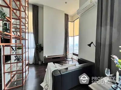 Modern living room with high ceilings and large windows offering city views.