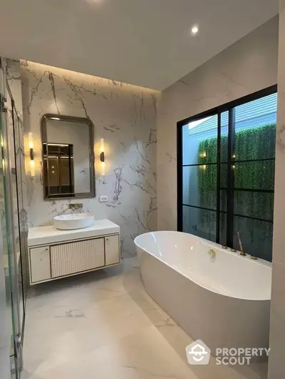 Luxurious bathroom with marble walls and flooring, freestanding tub, elegant vanity, and modern lighting, offering a serene spa-like retreat.