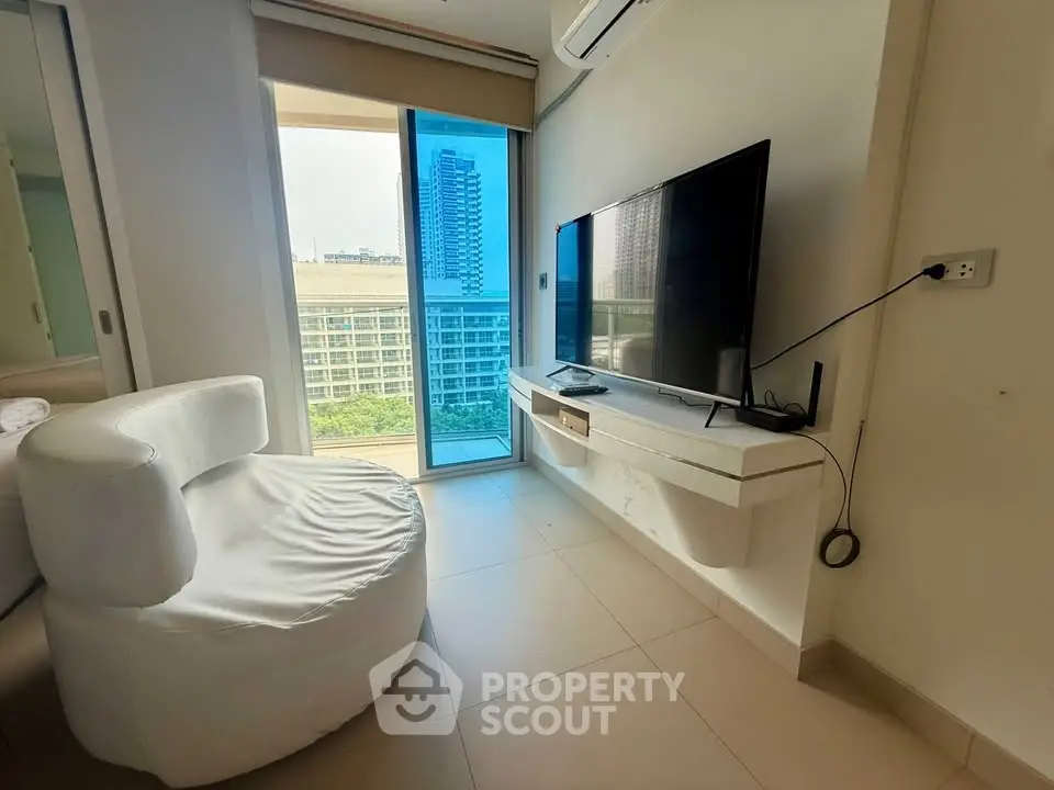Modern living room with sleek TV setup and city view from large window.