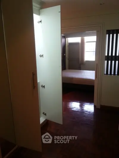 Spacious bedroom with wooden flooring and open closet door