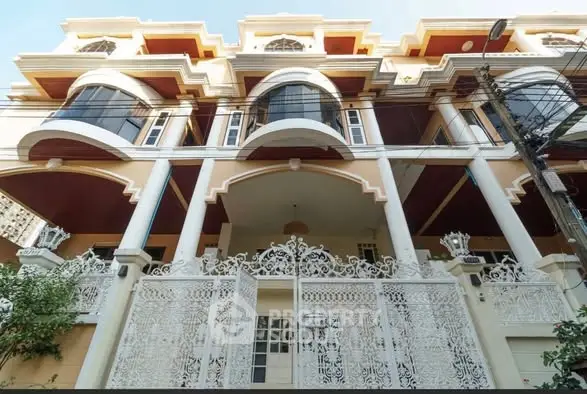 Stunning multi-story building with elegant architecture and ornate white gate, perfect for luxury living.