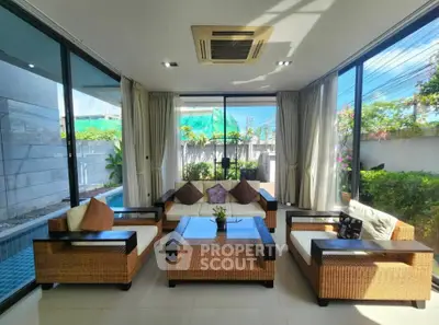 Luxurious living room with pool view and elegant wicker furniture, perfect for relaxation and entertaining.