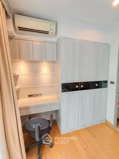 Modern study room with built-in desk and storage, featuring wooden flooring and air conditioning.