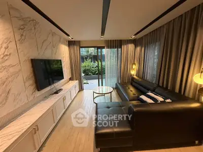 Luxurious living room with modern decor and garden view, featuring a sleek black leather sofa and marble accents.