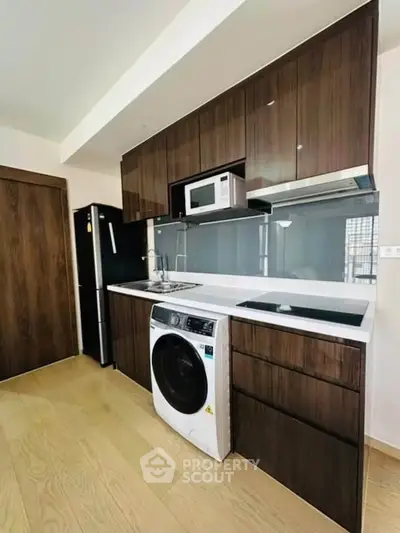 Modern kitchen with sleek cabinetry, built-in appliances, and wood flooring in a stylish apartment.