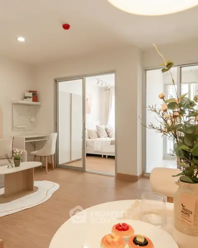 Modern open-plan living room with sliding doors to a cozy bedroom, stylish decor, and natural light.