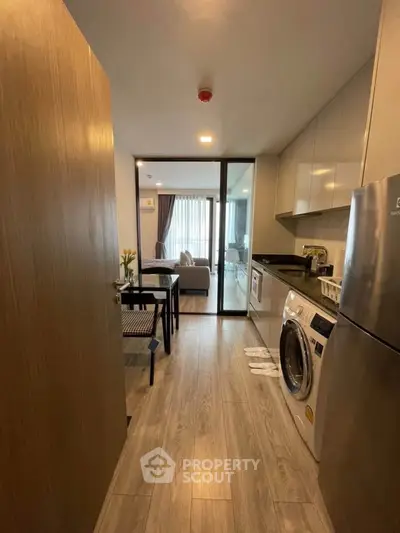 Modern open-layout kitchen with washing machine and dining area leading to a cozy living room.