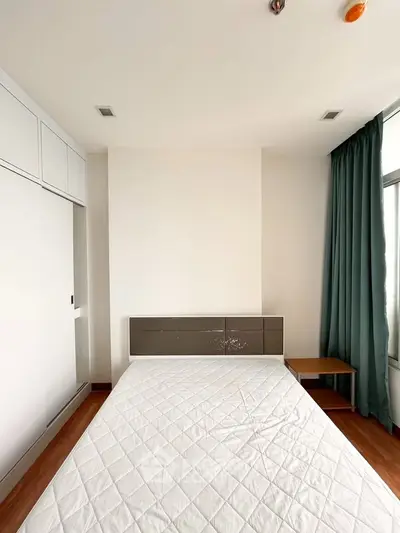 Spacious bedroom with modern design and ample natural light, featuring a comfortable bed and stylish decor.