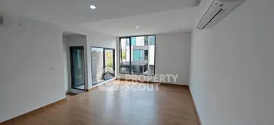 Spacious modern living room with large windows and wooden flooring, perfect for natural light lovers.